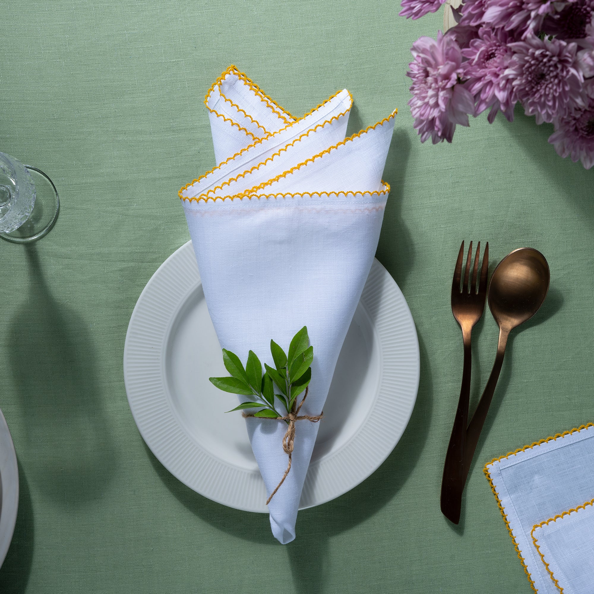 Close-up of the whipstitch edge on white and yellow pure linen dinner napkins