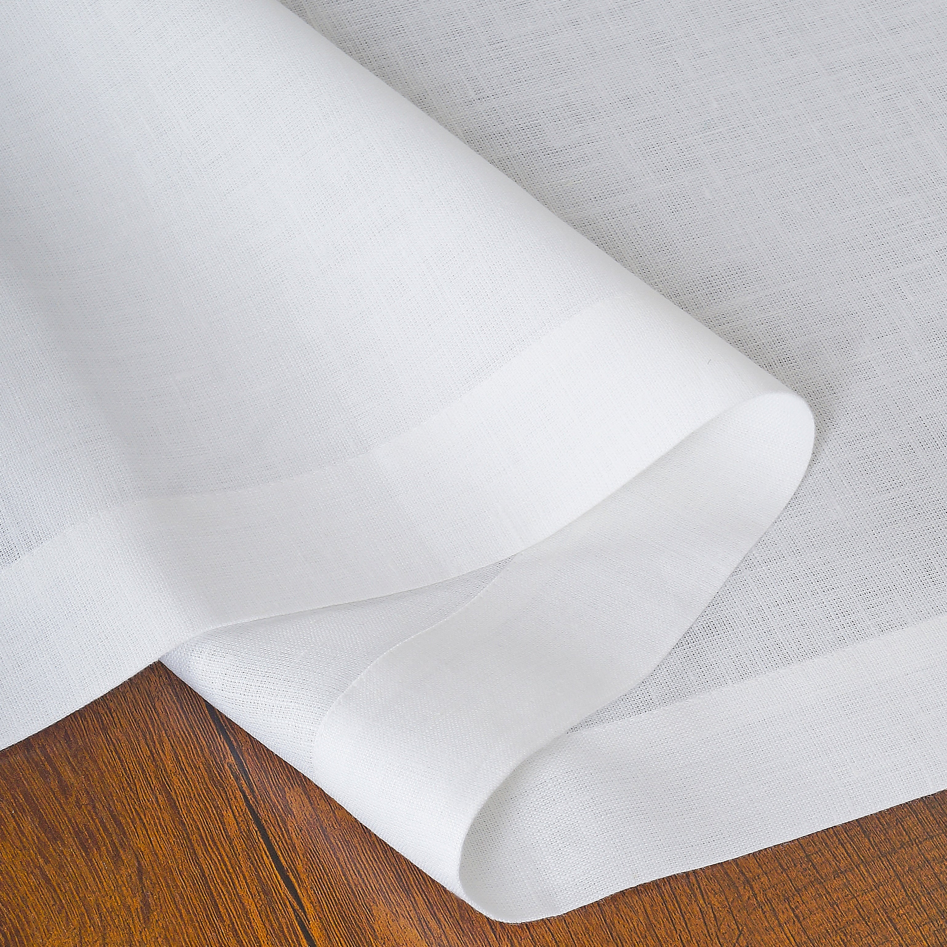 Close-up of the hemmed edge on a white linen table runner