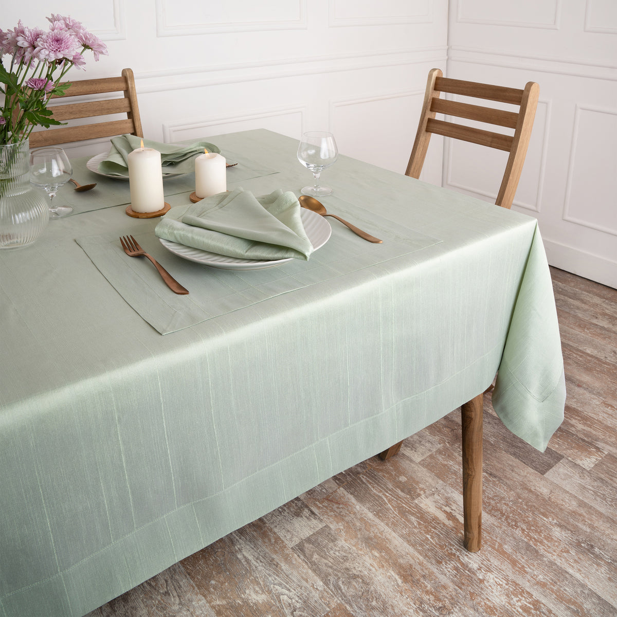Close-up of the mitered corners on a sage green Luxe Shine tablecloth