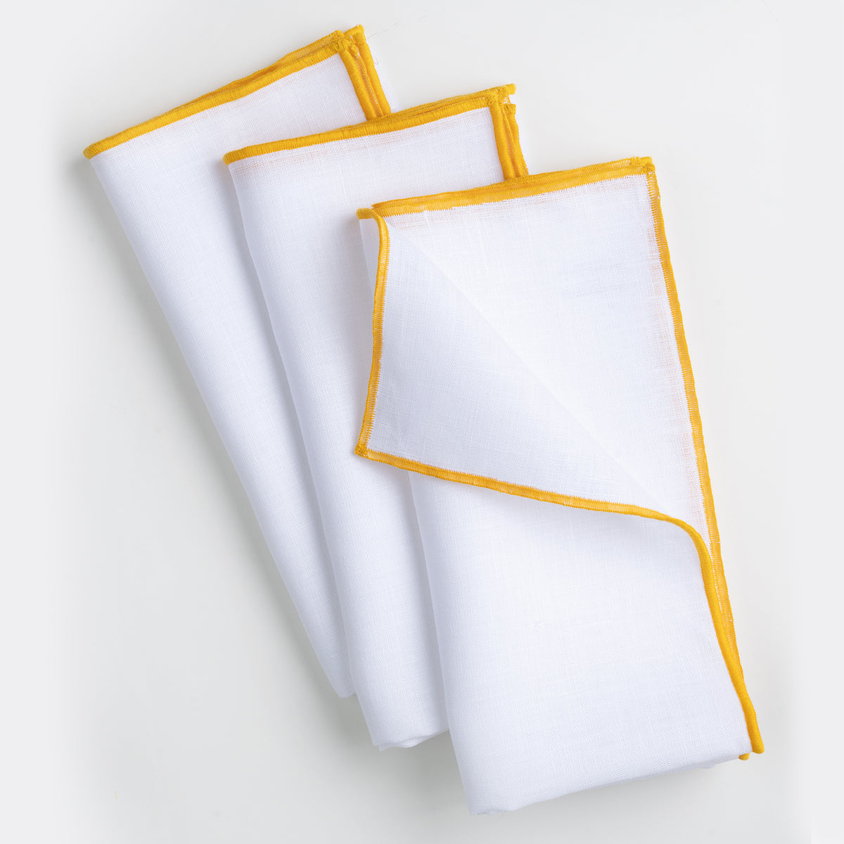 Close-up of the marrow edge on white and yellow pure linen dinner napkins