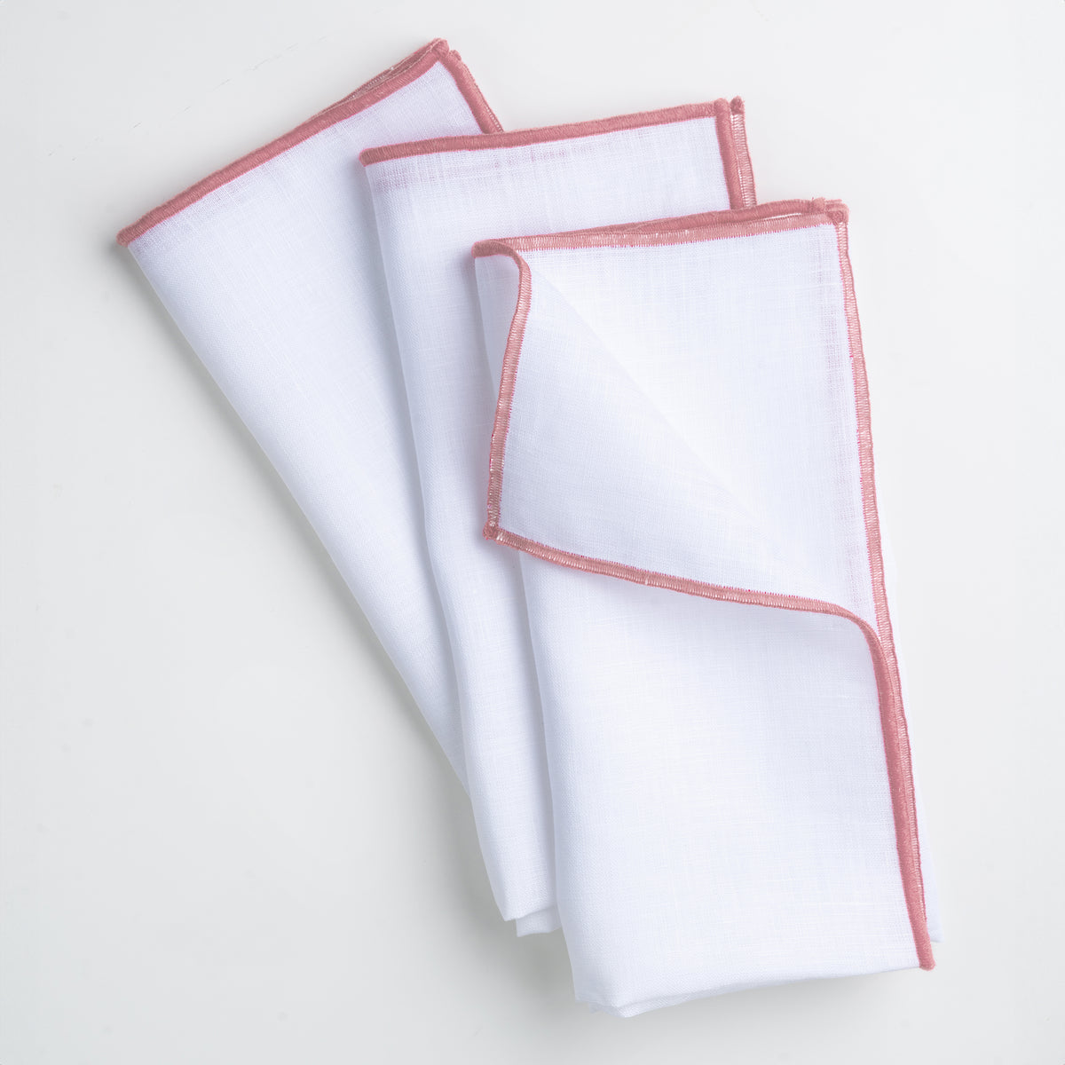Close-up of the marrow edge on white and dusty pink pure linen dinner napkins