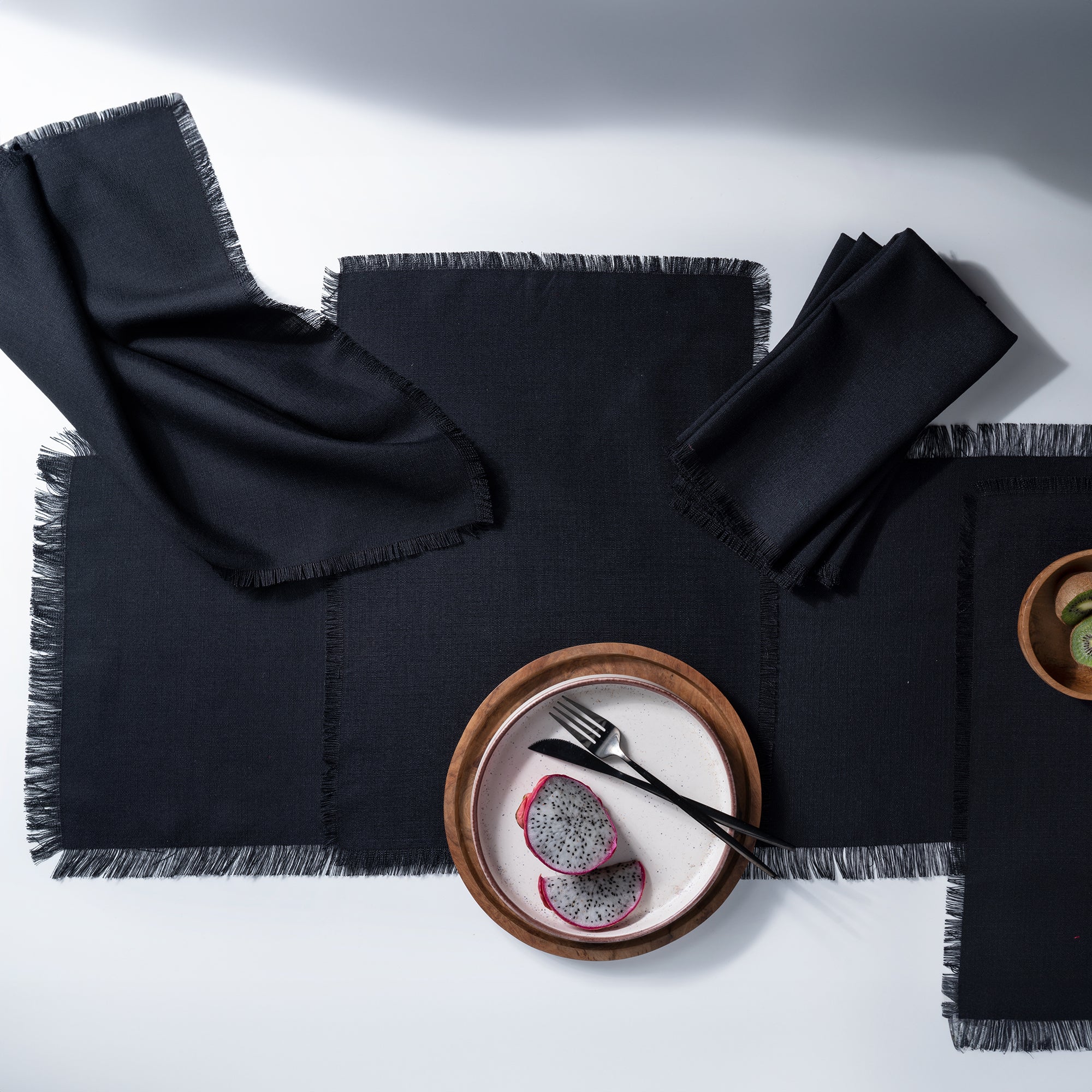 Black faux linen placemats folded to show fabric texture