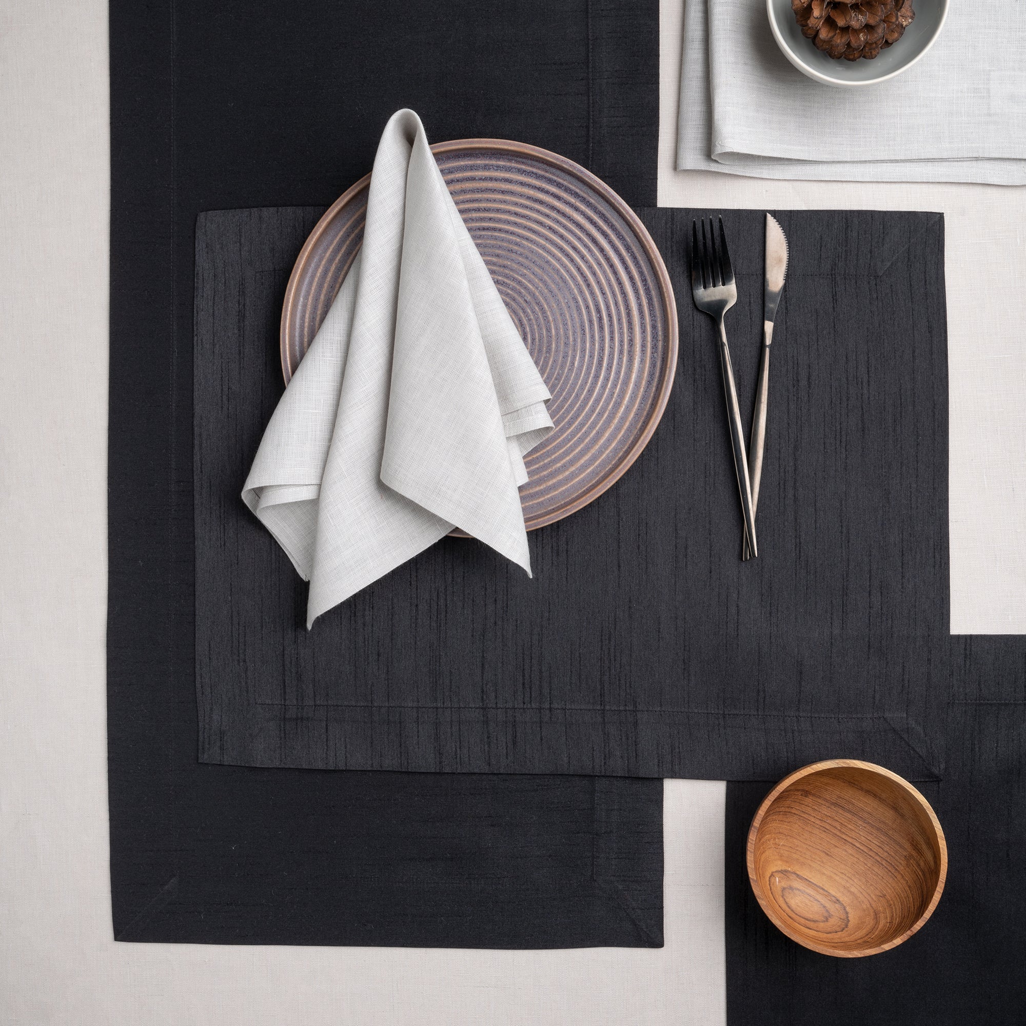 Close-up of the mitered corners on charcoal grey Luxe Shine placemats