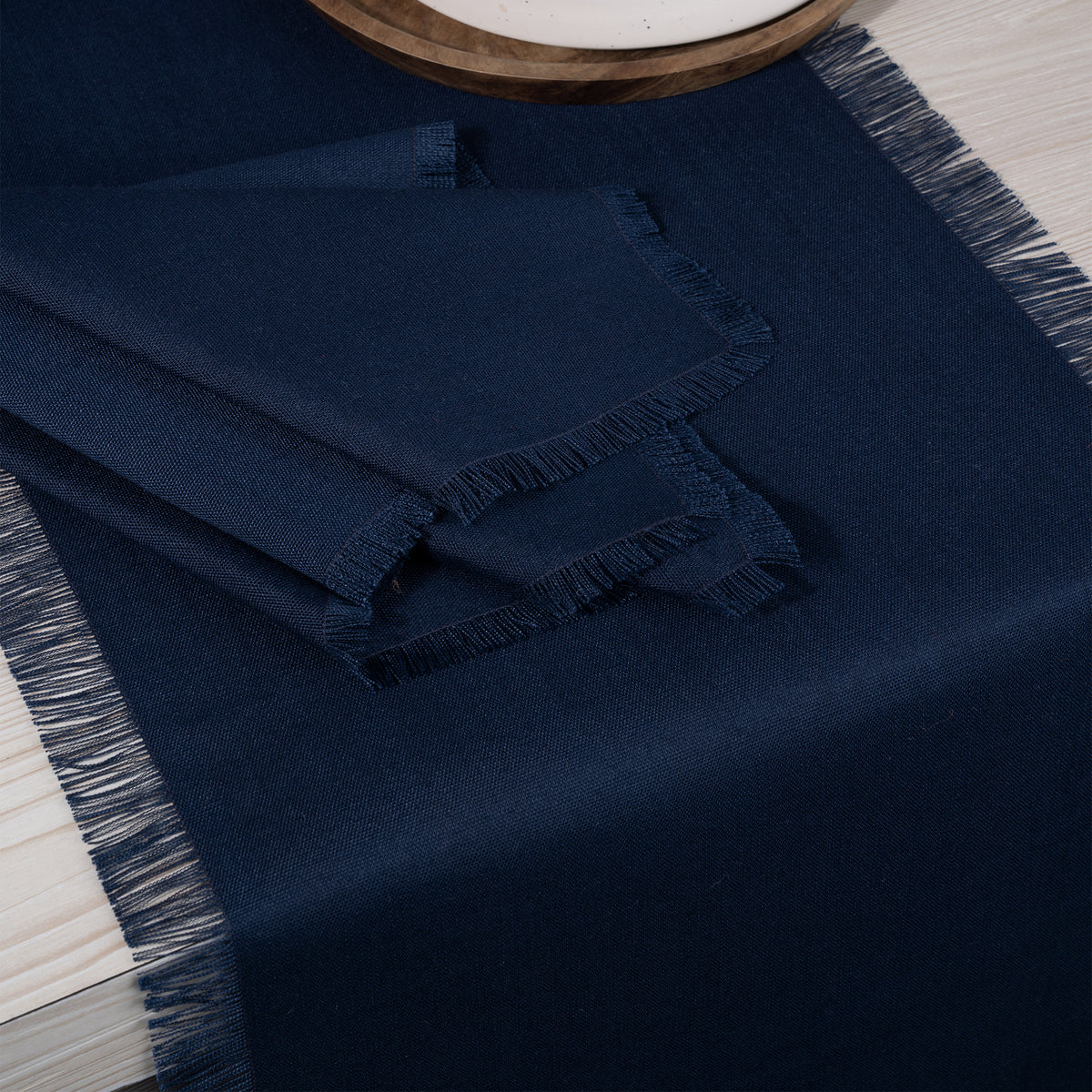 Close-up of the fringed edge on a navy blue faux linen table runner